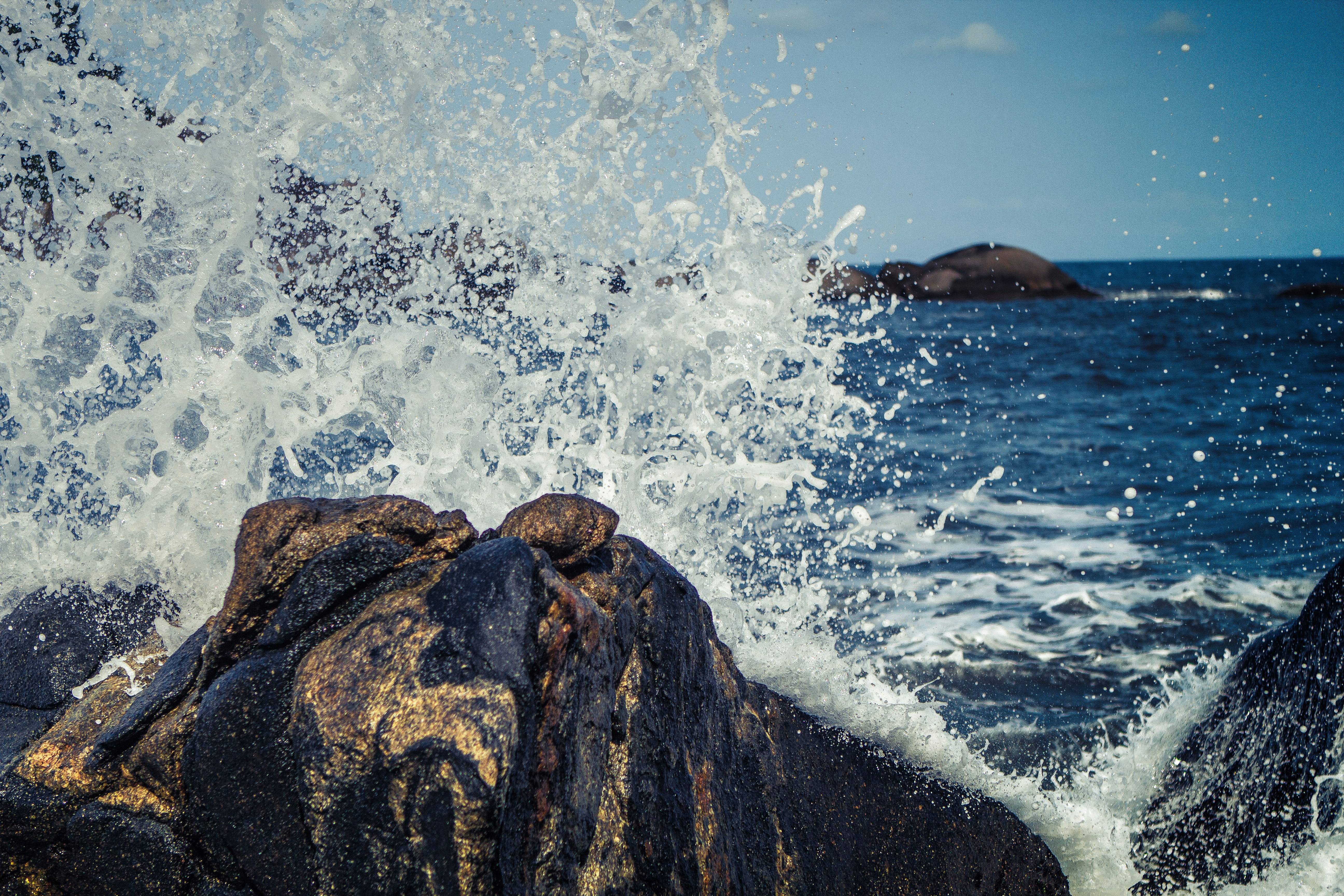 seawater splashing rock boulders at daytime
